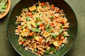 A bowl of homemade fried rice with  scrambled egg, vegetables, and green onions tossed with coconut aminos and soy sauce