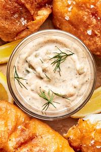 a bowl of homemade tartar sauce surrounded by beer battered fish and fries