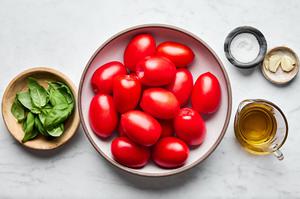 tomatoes, olive oil, salt, garlic and fresh basil in prep bowls to make homemade tomato sauce