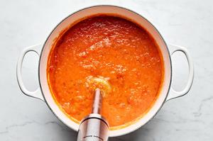 tomatoes, olive oil, salt, garlic and fresh basil in a pot being blended with an immersion blender