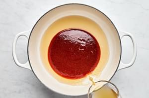 chicken stock and apple cider vinegar being added to a pot with homemade honey chipotle sauce