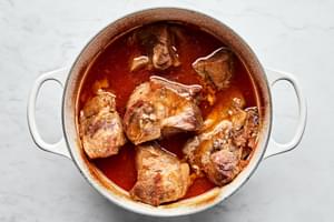 pork shoulder cooking in a pot with homemade honey chipotle sauce