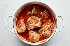 pork shoulder cooking in a pot with homemade honey chipotle sauce