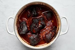 pork shoulder cooking in a pot with homemade honey chipotle sauce