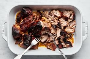 honey chipotle pulled pork being shred with 2 forks in a serving dish
