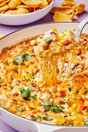 hot corn dip in a skillet made with cream cheese, butter, sour cream, mayo, cheese, jalapeño and spices