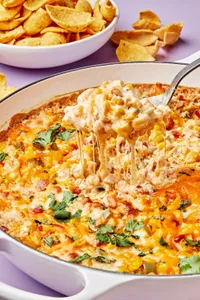 hot corn dip in a skillet made with cream cheese, butter, sour cream, mayo, cheese, jalapeño and spices
