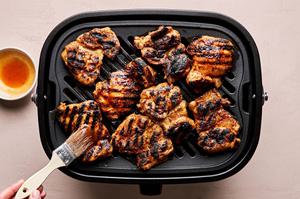 hot honey chicken being grilled and brushed with hot honey sauce