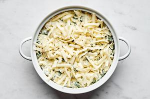spinach and artichoke dip topped with mozzarella in a baking dish ready for the oven