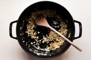 onions softened in olive oil in a soup pot with a wooden spoon