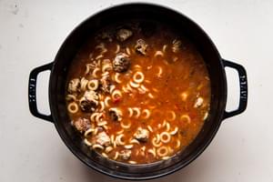 tomato based Italian meatball soup in a soup pot with pasta