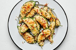 Plate of homemade jalapeño poppers stuffed with creamy cheese filling and bacon with a crispy golden breading.