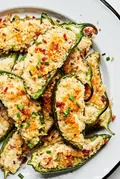 Plate of homemade jalapeño poppers stuffed with creamy cheese filling and bacon with a crispy golden breading.