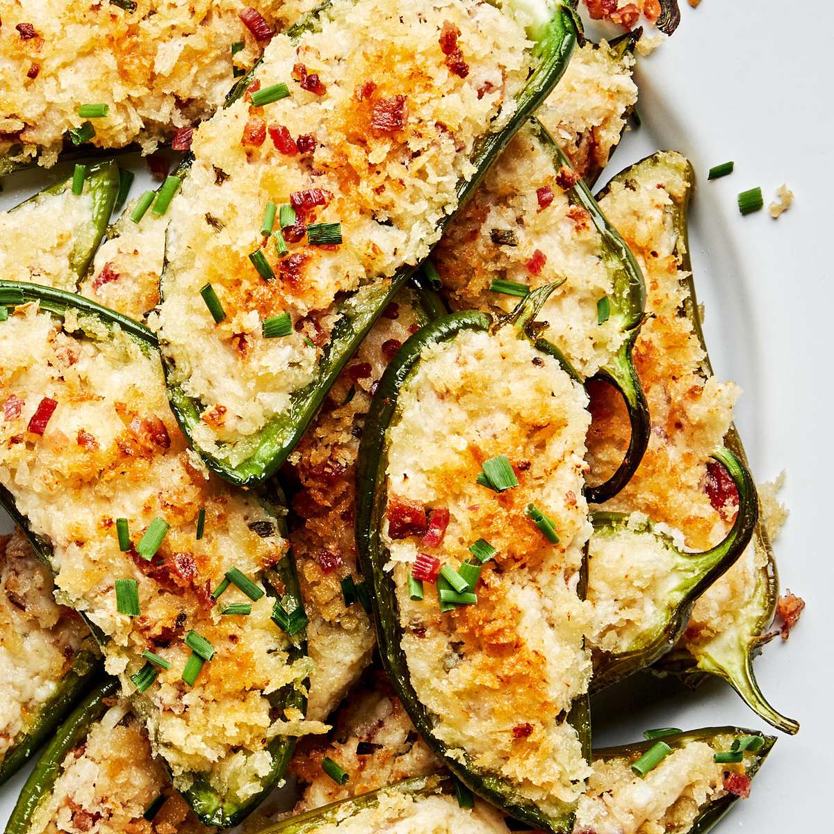 Plate of homemade jalapeño poppers stuffed with creamy cheese filling and bacon with a crispy golden breading.