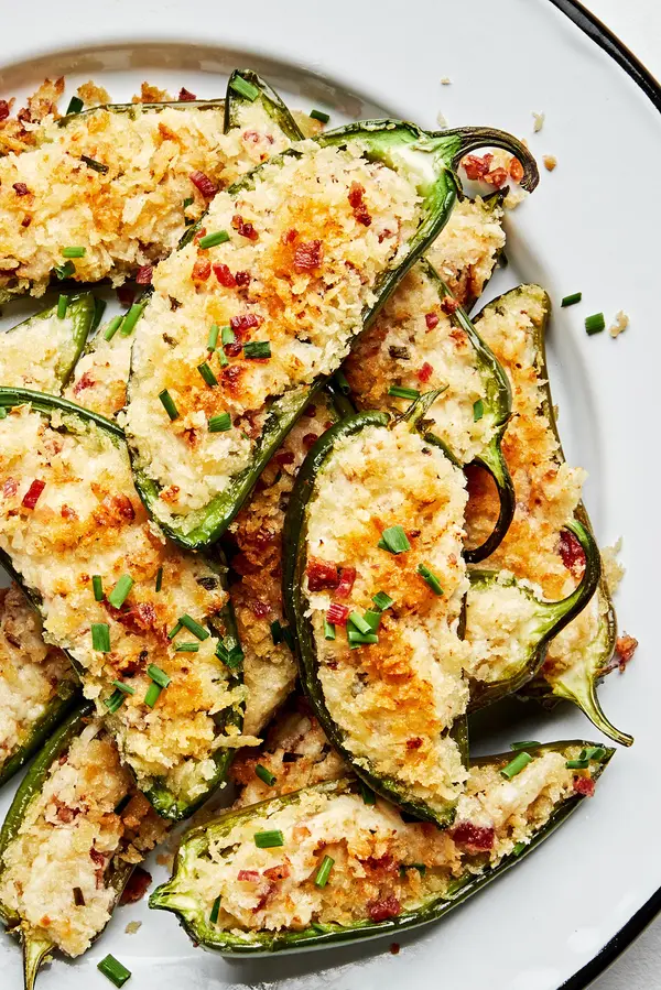 Plate of homemade jalapeño poppers stuffed with creamy cheese filling and bacon with a crispy golden breading.