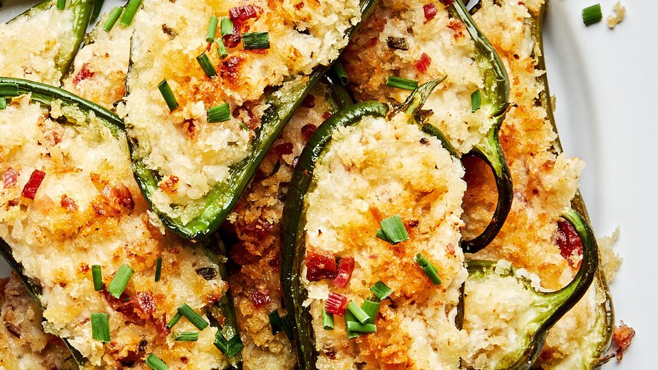 Plate of homemade jalapeño poppers stuffed with creamy cheese filling and bacon with a crispy golden breading.