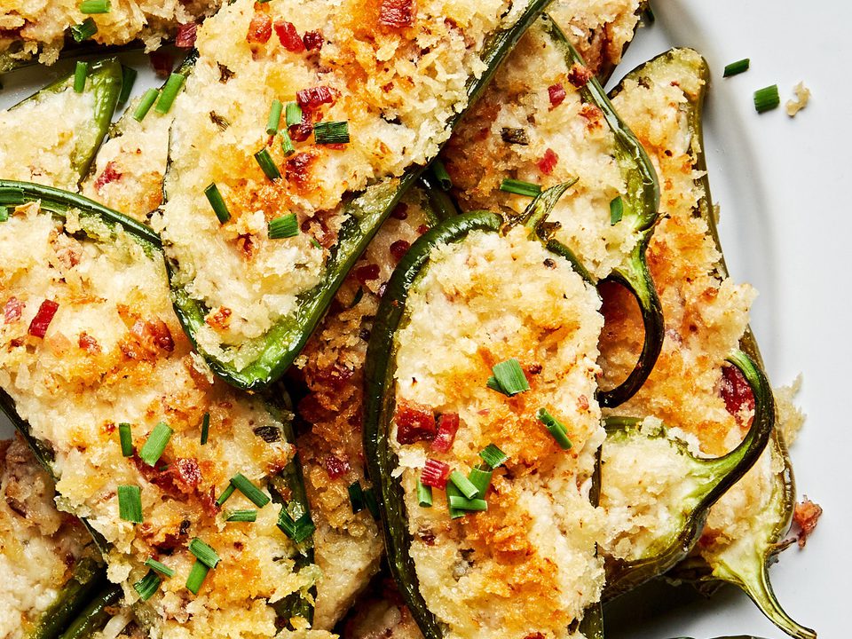 Plate of homemade jalapeño poppers stuffed with creamy cheese filling and bacon with a crispy golden breading.