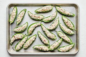 halved jalapenos filled with and creamy, cheesy filling topped with breadcrumbs ready to be baked
