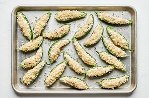 halved jalapenos filled with and creamy, cheesy filling topped with breadcrumbs ready to be baked