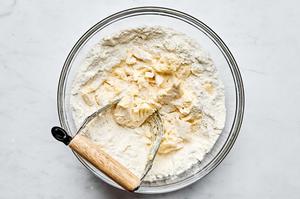 butter being cut into flour, baking soda, baking powder, salt and sugar with a pastry cutter