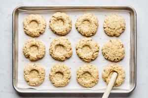 wells being made with a wooden spoon in partially baked oat scones on a parchment lined baking sheet