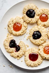 a plate of homemade jam dot oat scones filled with assorted fruit jams