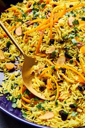a bowl of jeweled rice made with pistachios, almonds, shallot, turmeric, cumin, cinnamon, all spice, salt and dried fruit