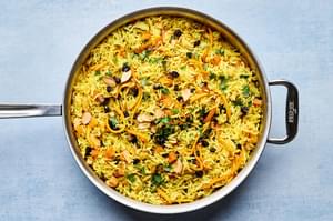 a pot of jeweled rice made with pistachios, almonds, shallot, turmeric, cumin, cinnamon, all spice, salt and dried fruit