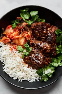 korean style pot roast in a bowl served with white rice and kimchi and topped with cilantro