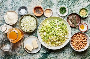 Ingredients for leek soup in small bowls including chickpeas, leeks, chicken stock, onions, heavy cream and thyme.