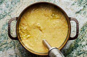 immersion blender blending leek soup in a large cast iron pot