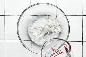 cornstarch and water being combined in a glass bowl