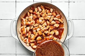 lemon teriyaki sauce being poured over cooked chicken in a skillet