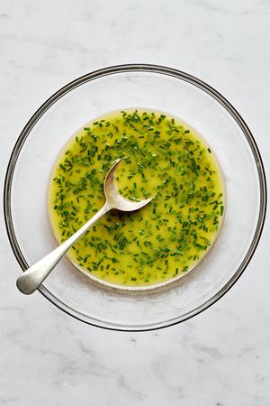 homemade lemon vinaigrette in a bowl with a spoon made with lemon juice, dijon mustard, sugar, salt, olive oil and chives