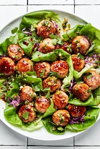 Lemongrass Meatball Lettuce Cups sprinkled with fresh herbs, drizzle with brown sugar sauce and green onion oil.