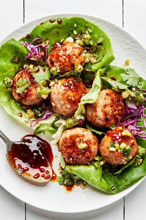 Lemongrass Meatball Lettuce Cups sprinkled with fresh herbs, drizzle with brown sugar sauce and green onion oil.