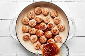 brown sugar suace being poured over browned lemongrass meatballs in a skillet