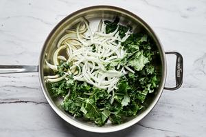 kale and onions being cooked in olive oil in a skillet