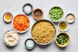 macaroni, carrots, relish, celery, green onions, mayo, sugar, honey, and spices in prep bowls to make macaroni salad