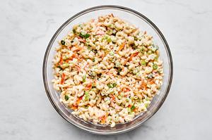 a bowl of macaroni salad made with Mayo, sugar, honey, spices, carrots, relish, celery and green onions