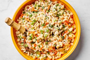 a bowl of macaroni salad made with Mayo, sugar, honey, spices, carrots, relish, celery and green onions