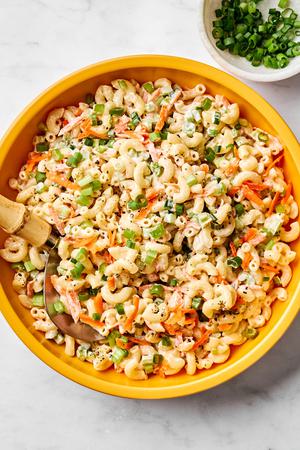 a bowl of macaroni salad made with Mayo, sugar, honey, spices, carrots, relish, celery and green onions