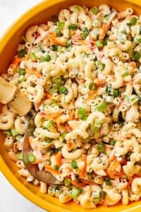 a bowl of macaroni salad made with Mayo, sugar, honey, spices, carrots, relish, celery and green onions