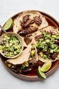 Margarita Beef tacos served in warm corn tortillas, topped with vibrant avocado salsa.