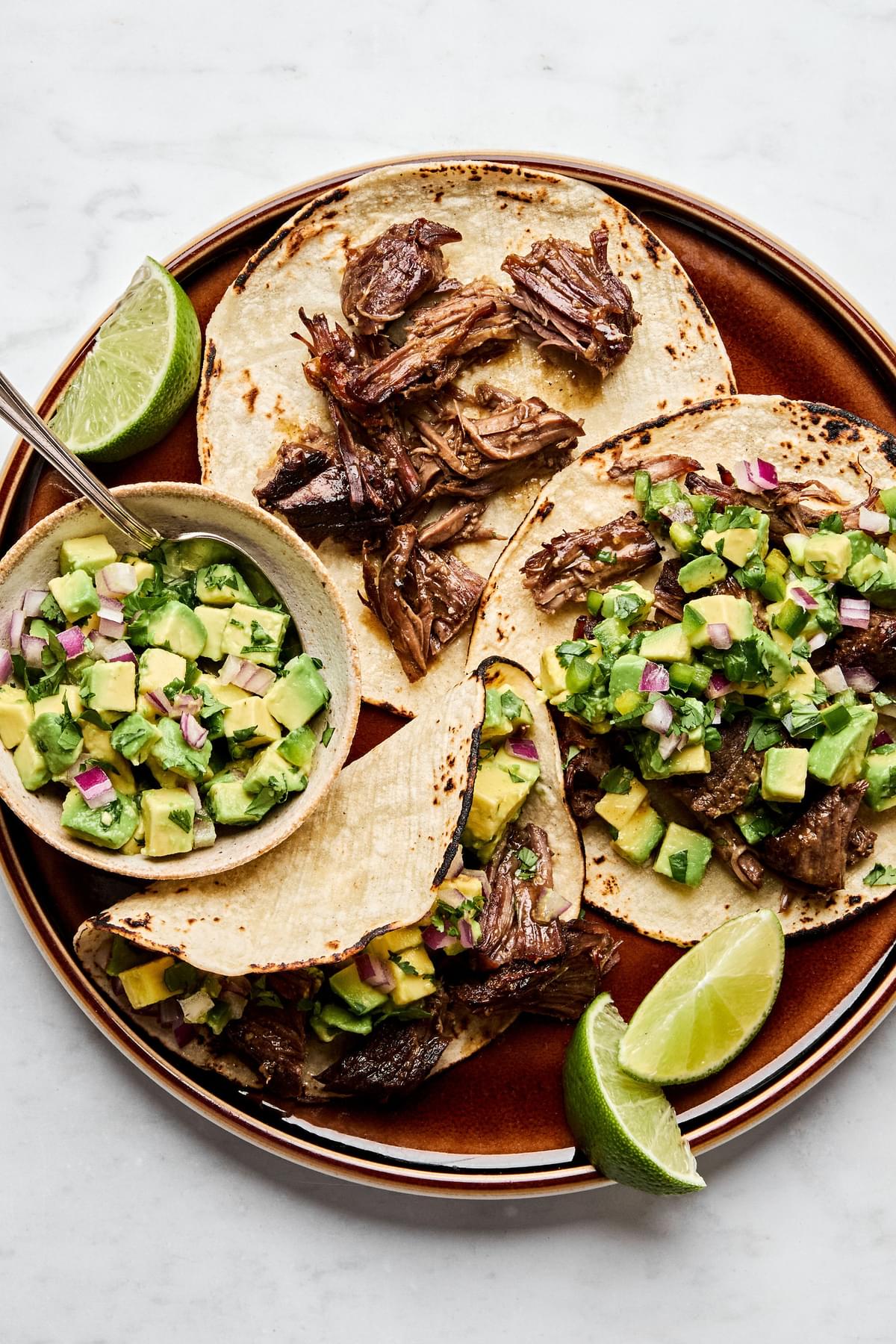 Margarita Beef tacos served in warm corn tortillas, topped with vibrant avocado salsa.