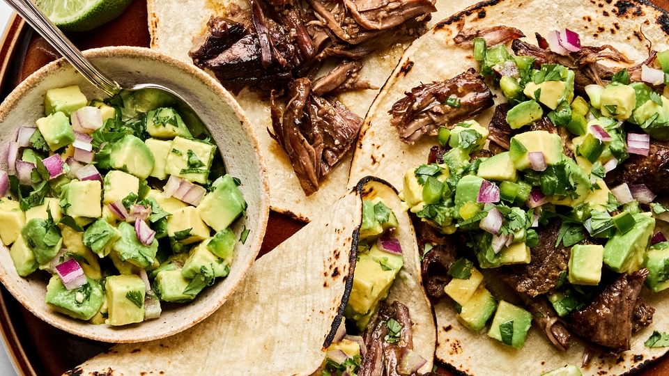 Margarita Beef tacos served in warm corn tortillas, topped with vibrant avocado salsa.