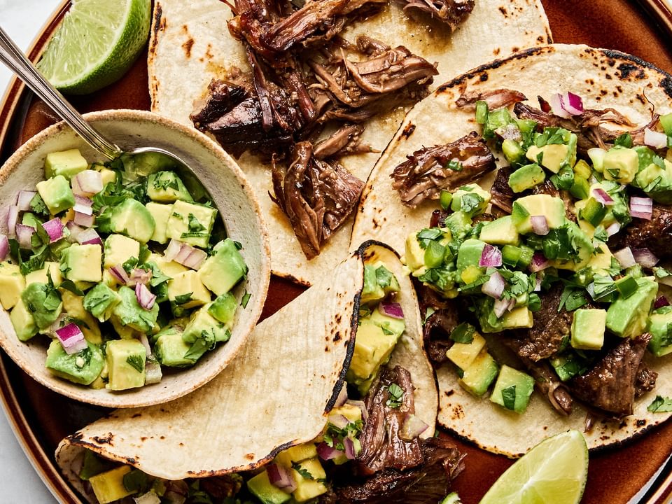 Margarita Beef tacos served in warm corn tortillas, topped with vibrant avocado salsa.