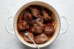 3 inch pieces of chuck roast seasoned with salt and pepper being browned in a pan