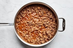 Meat pie filling cooking in a skillet, with a mix of pork, beef, mashed potatoes, onion, and spices