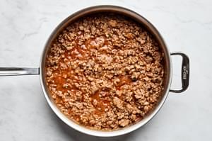 Meat pie filling cooking in a skillet, with a mix of pork, beef, mashed potatoes, onion, and spices